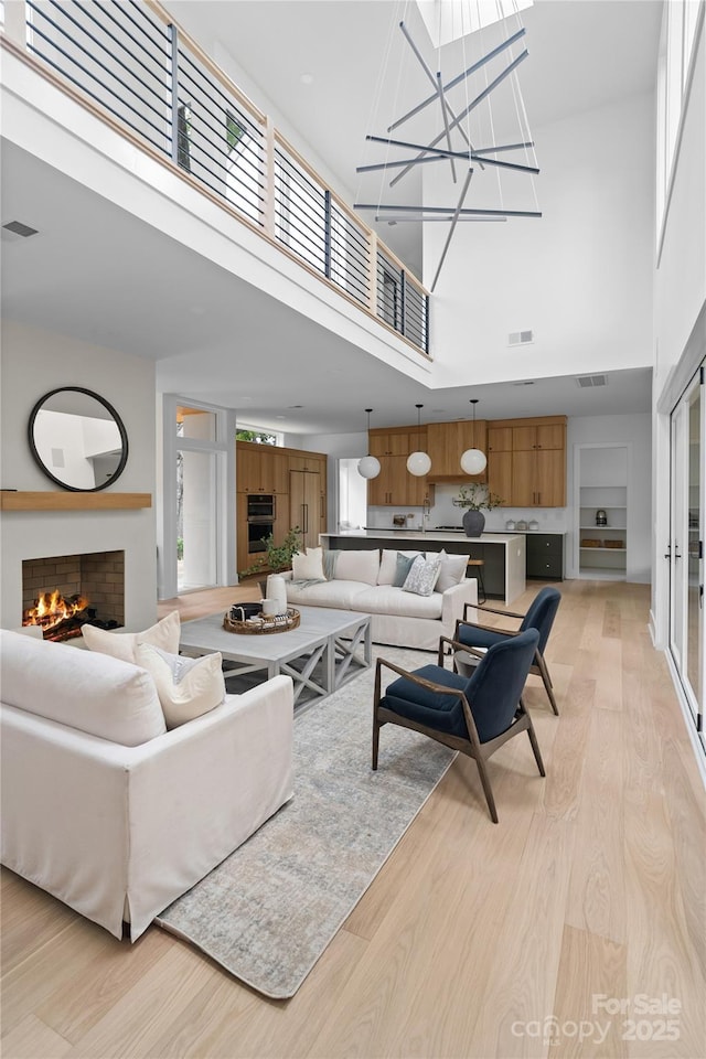 3822 Topsfield Rd, Charlotte, NC 28211 - living room featuring a high ceiling, a warm lit fireplace, light wood-style floors, and a chandelier