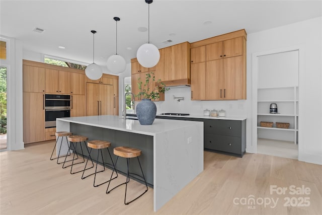 3822 Topsfield Rd, Charlotte, NC 28211 - kitchen featuring stainless steel double oven, light wood finished floors, modern cabinets, and a center island with sink