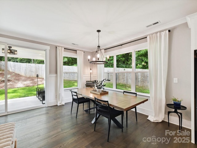 2517 Marlowe Ave, Charlotte, NC 28208 - dining area with a chandelier, plenty of natural light, dark wood finished floors, a wainscoted wall, and ornamental molding