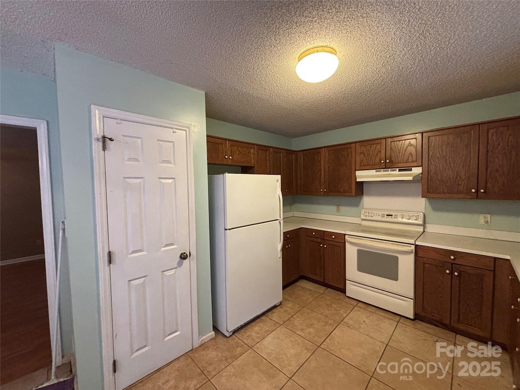 8819 Noah Helms Rd, Indian Trail, NC 28079 - kitchen featuring white appliances, under cabinet range hood, a textured ceiling, light countertops, and light tile patterned floors