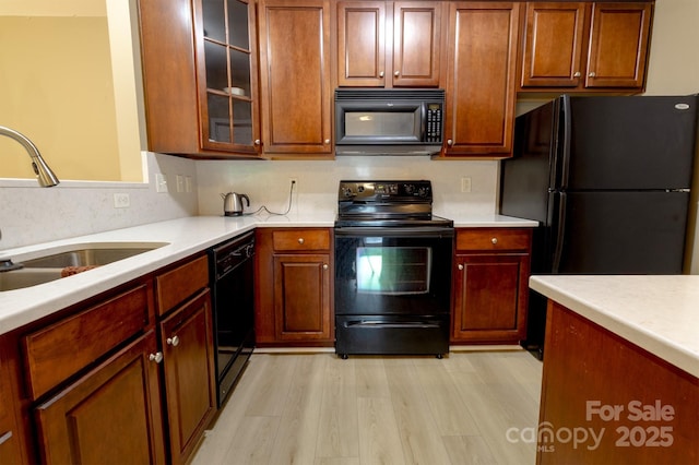11867 Ridgeway Park Dr, Charlotte, NC 28277 - kitchen with black appliances, light countertops, light wood-type flooring, and glass insert cabinets