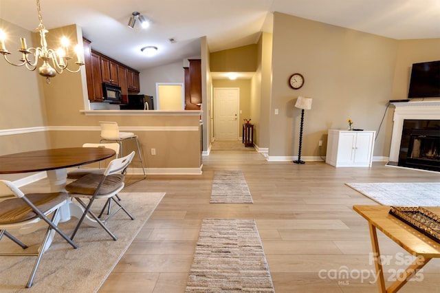 11867 Ridgeway Park Dr, Charlotte, NC 28277 - dining space with a fireplace, a chandelier, light wood-type flooring, and lofted ceiling