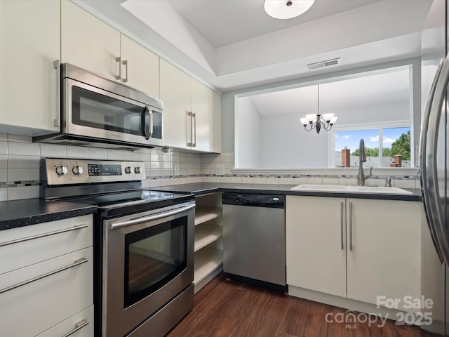 9404 S Vicksburg Park Ct, Charlotte, NC 28210 - kitchen with stainless steel appliances, a sink, dark countertops, white cabinets, and a chandelier