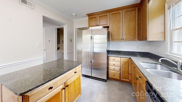 2507 Birnen Dr, Charlotte, NC 28210 - kitchen with freestanding refrigerator, a sink, light tile patterned floors, brown cabinetry, and dark stone counters