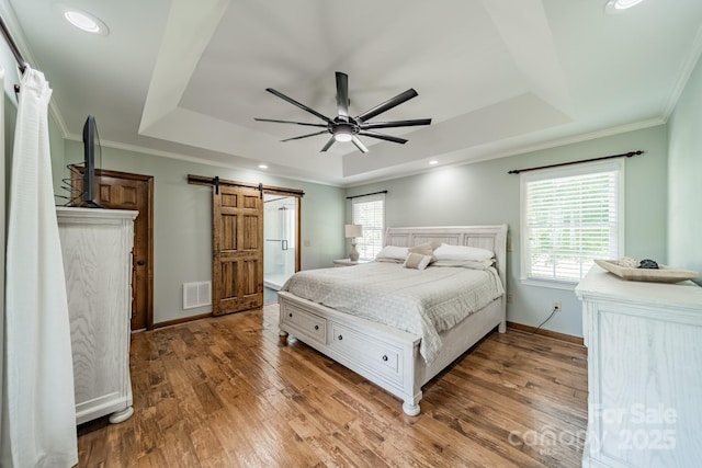 8698 Rocky River Rd, Harrisburg, NC 28075 - bedroom featuring a tray ceiling, a barn door, wood finished floors, crown molding, and baseboards