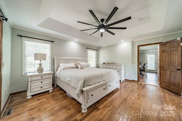 8698 Rocky River Rd, Harrisburg, NC 28075 - bedroom featuring a tray ceiling, wood-type flooring, multiple windows, baseboards, and crown molding