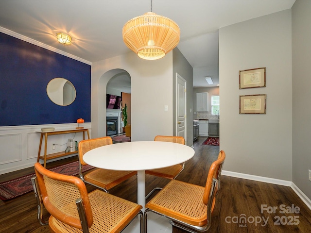 10639 Secret Garden Ln, Charlotte, NC 28214 - dining room featuring arched walkways, wood finished floors, a glass covered fireplace, and baseboards