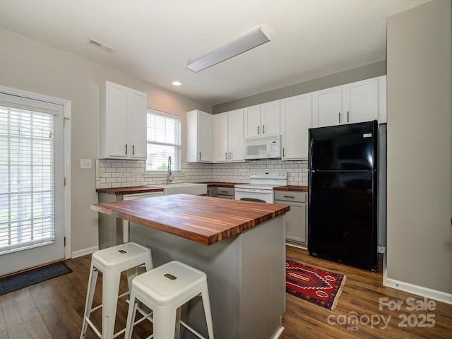 10639 Secret Garden Ln, Charlotte, NC 28214 - kitchen with butcher block countertops, white appliances, a sink, a breakfast bar area, and backsplash