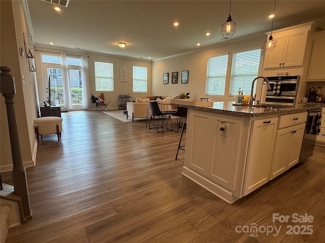 1016 Laggan Ln, Indian Trail, NC 28079 - kitchen with open floor plan, oven, ornamental molding, an island with sink, and white cabinets