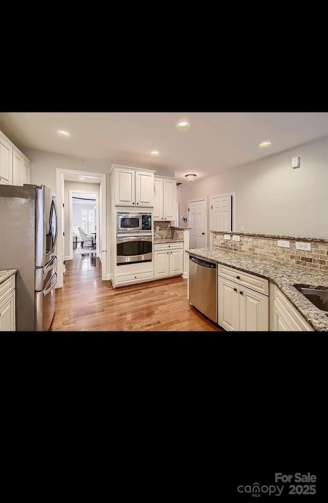 2234 Donnington Ln NW, Concord, NC 28027 - kitchen with appliances with stainless steel finishes, decorative backsplash, light wood-style flooring, white cabinetry, and recessed lighting