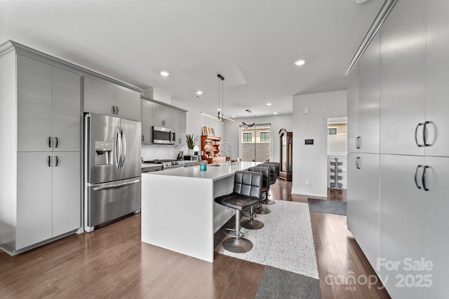 919 Cityscape Dr, Charlotte, NC 28205 - kitchen with appliances with stainless steel finishes, gray cabinets, a sink, dark wood-style flooring, and a center island with sink