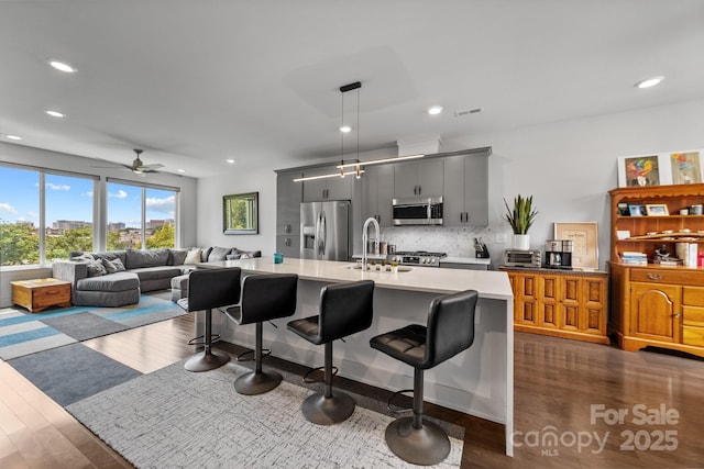 919 Cityscape Dr, Charlotte, NC 28205 - kitchen with appliances with stainless steel finishes, a breakfast bar area, dark wood-type flooring, light countertops, and recessed lighting