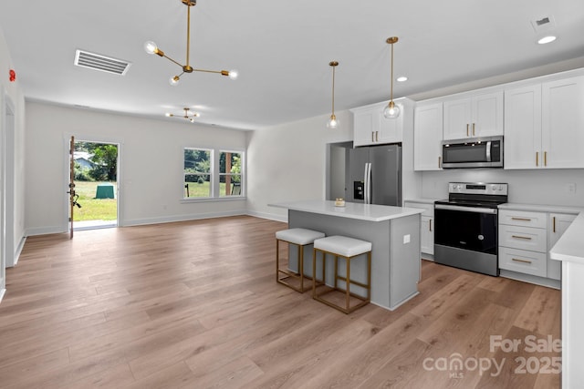 2220 Mooresville Rd, Salisbury, NC 28147 - kitchen with stainless steel appliances, a center island, light countertops, light wood-type flooring, and a chandelier