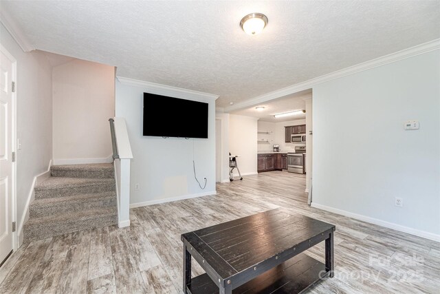 503 Apple St, Gibsonville, NC 27249 - unfurnished living room featuring a textured ceiling, light wood-style floors, crown molding, baseboards, and stairs