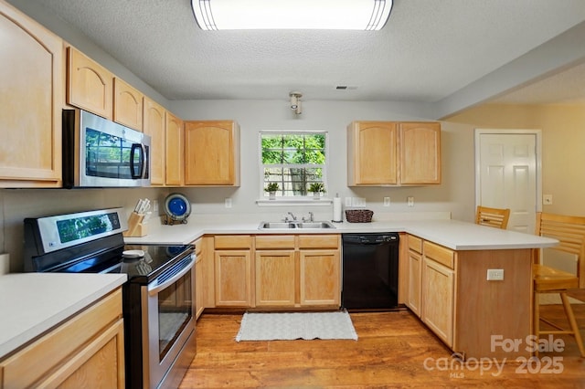 820 Settlement St, Clover, SC 29710 - kitchen featuring stainless steel appliances, light brown cabinets, a peninsula, light wood-style floors, and a textured ceiling
