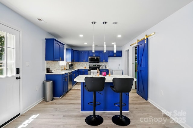 1005 Exodus Ct, Monroe, NC 28110 - kitchen with stainless steel appliances, blue cabinets, a barn door, light wood-style flooring, and tasteful backsplash