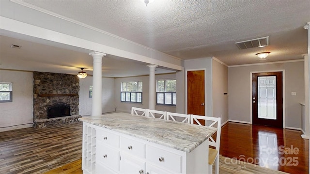 3151 Lynn Mountain Rd, Vale, NC 28168 - kitchen with dark wood-style flooring, ornate columns, a textured ceiling, white cabinets, and a fireplace