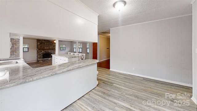 3151 Lynn Mountain Rd, Vale, NC 28168 - kitchen with light wood-style floors, a stone fireplace, white cabinets, a textured ceiling, and a peninsula