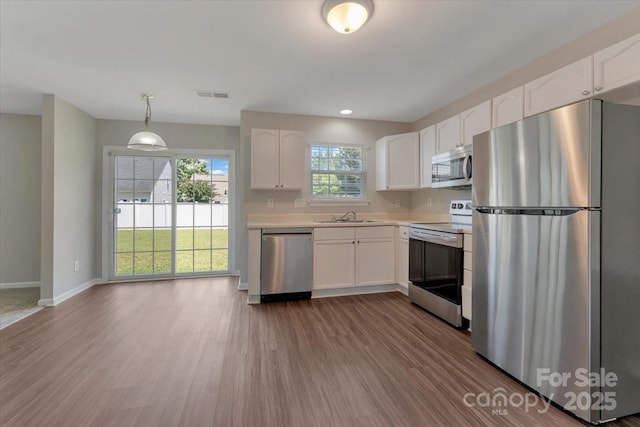 1111 Balcorn Pl, Charlotte, NC 28214 - kitchen with stainless steel appliances, a sink, wood finished floors, white cabinets, and recessed lighting