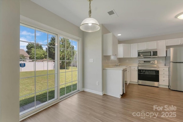 1111 Balcorn Pl, Charlotte, NC 28214 - kitchen with stainless steel appliances, light countertops, wood finished floors, white cabinetry, and baseboards