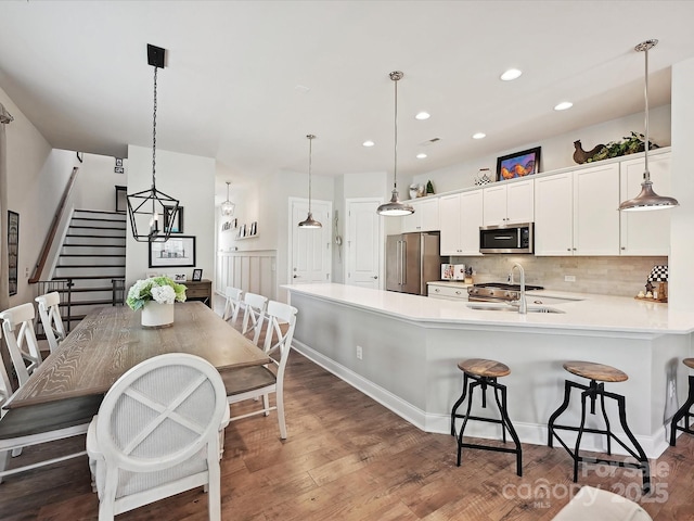 9405 Gladden Hill Ln, Pineville, NC 28134 - kitchen with stainless steel appliances, light countertops, a kitchen breakfast bar, white cabinetry, and decorative backsplash