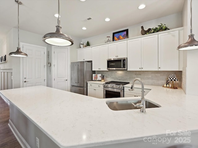 9405 Gladden Hill Ln, Pineville, NC 28134 - kitchen with stainless steel appliances, a sink, a peninsula, decorative backsplash, and white cabinetry