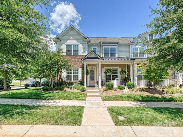 9405 Gladden Hill Ln, Pineville, NC 28134 - view of property with covered porch, brick siding, a standing seam roof, a front yard, and a shingled roof