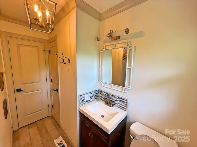 5033 Baylor Dr, Charlotte, NC 28210 - half bathroom with toilet, vanity, ornamental molding, a chandelier, and wood finished floors