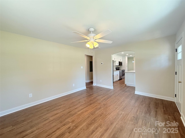 111 W Perry St, Heath Springs, SC 29058 - unfurnished living room featuring wood finished floors, a ceiling fan, arched walkways, and baseboards