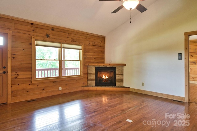 496 Moonlight Pass, Union Mills, NC 28167 - unfurnished living room featuring wooden walls, lofted ceiling, wood finished floors, a stone fireplace, and a ceiling fan