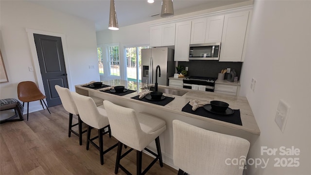 6386 Cathedral Dr, Granite Falls, NC 28601 - kitchen featuring stainless steel appliances, a sink, white cabinetry, a kitchen breakfast bar, and decorative backsplash