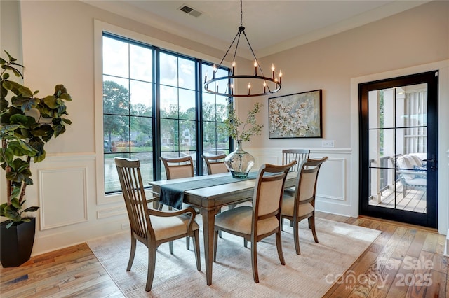 445 Sundown Rd, Mooresville, NC 28117 - dining area with a decorative wall, light wood-style floors, a chandelier, and wainscoting