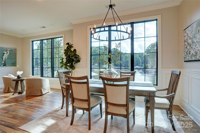 445 Sundown Rd, Mooresville, NC 28117 - dining space with a decorative wall, wood finished floors, a wainscoted wall, ornamental molding, and a chandelier