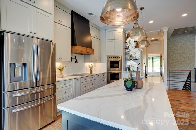 445 Sundown Rd, Mooresville, NC 28117 - kitchen with appliances with stainless steel finishes, custom range hood, light wood-style floors, light stone counters, and pendant lighting