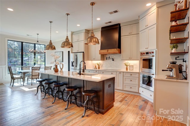 445 Sundown Rd, Mooresville, NC 28117 - kitchen featuring a sink, stainless steel appliances, a breakfast bar area, premium range hood, and light wood-style flooring