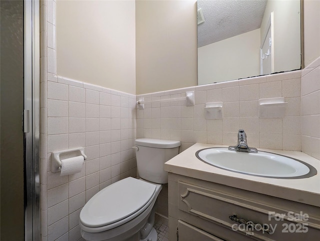 5628 White Store Rd, Wingate, NC 28174 - bathroom featuring tile walls, toilet, vanity, a textured ceiling, and wainscoting