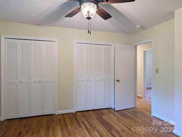 5628 White Store Rd, Wingate, NC 28174 - unfurnished bedroom with two closets, wood finished floors, baseboards, a textured ceiling, and ceiling fan