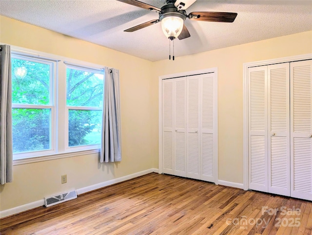 5628 White Store Rd, Wingate, NC 28174 - unfurnished bedroom with multiple closets, wood finished floors, multiple windows, and a textured ceiling