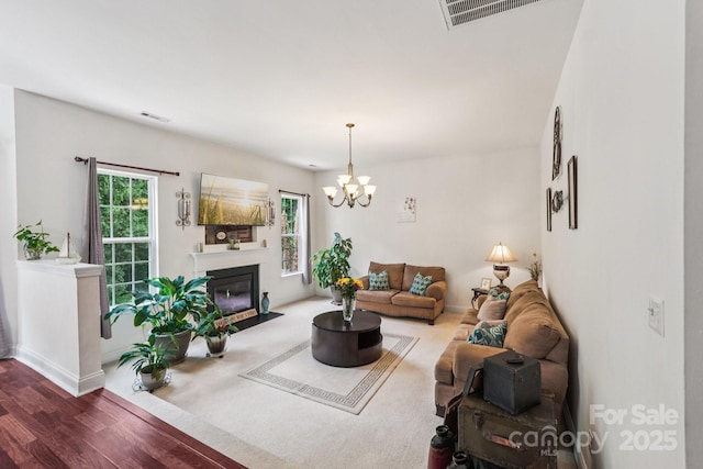 5021 Meadow Woods Dr, Lowell, NC 28098 - living room featuring wood finished floors, a chandelier, a fireplace with flush hearth, and baseboards