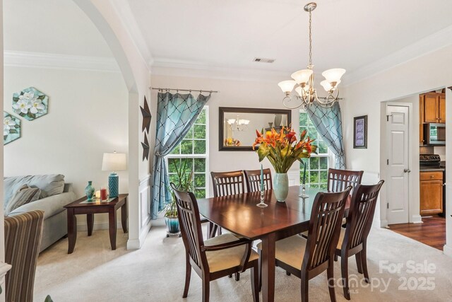 5021 Meadow Woods Dr, Lowell, NC 28098 - dining space featuring a chandelier, arched walkways, crown molding, light carpet, and baseboards