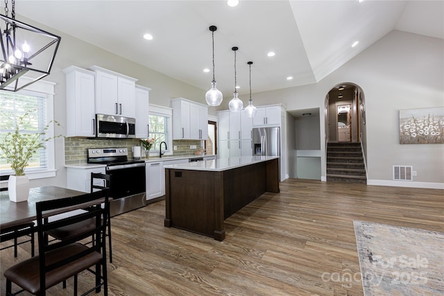 8340 Brief Rd, Mint Hill, NC 28227 - kitchen featuring appliances with stainless steel finishes, light countertops, a center island, wood finished floors, and lofted ceiling