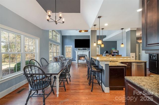 6057 Erie View Ct, Denver, NC 28037 - dining area featuring light wood-style floors, baseboards, a warm lit fireplace, a chandelier, and recessed lighting