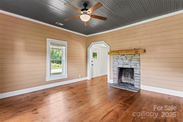 233 Sellars Rd, Kings Mountain, NC 28086 - unfurnished living room featuring wooden walls, hardwood / wood-style floors, an outdoor stone fireplace, a ceiling fan, and baseboards