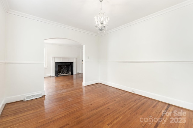 1400 Matheson Ave, Charlotte, NC 28205 - unfurnished living room with arched walkways, baseboards, wood finished floors, crown molding, and a chandelier