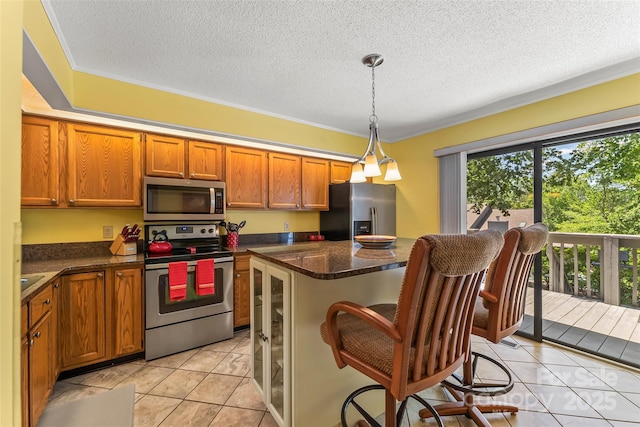 903 Independence Trl, Morganton, NC 28655 - kitchen with appliances with stainless steel finishes, light tile patterned floors, brown cabinetry, a textured ceiling, and a kitchen island