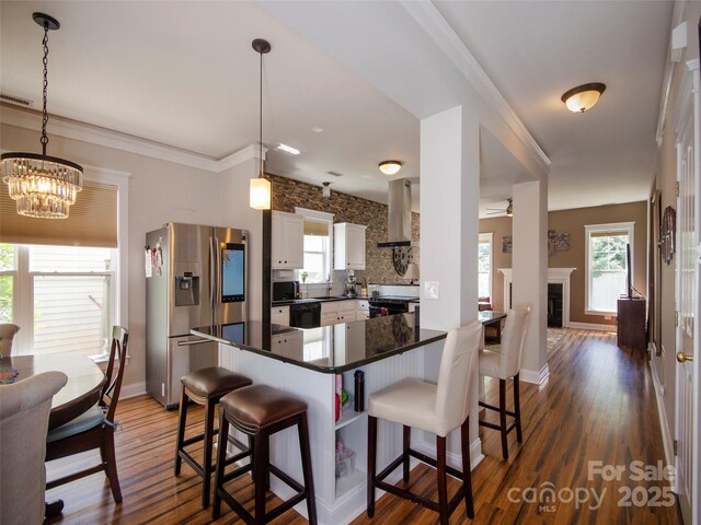 1410 Kenton Ln, Asheville, NC 28803 - kitchen featuring stainless steel refrigerator with ice dispenser, wall chimney range hood, black dishwasher, dark countertops, and a breakfast bar area