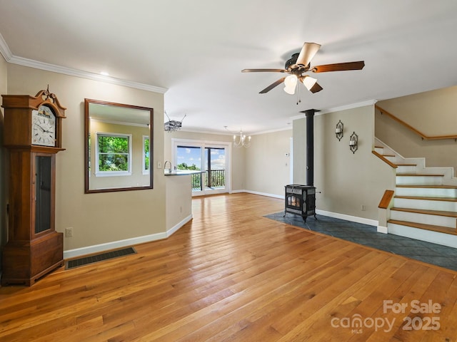 58 Randall Dr, Fairview, NC 28730 - unfurnished living room with crown molding, a wood stove, light wood-type flooring, a chandelier, and stairway