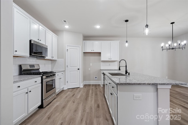6712 W Sugar Creek Rd, Charlotte, NC 28269 - kitchen with stainless steel appliances, a sink, light wood-style floors, white cabinetry, and decorative backsplash
