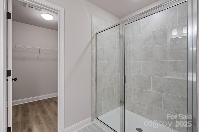 6712 W Sugar Creek Rd, Charlotte, NC 28269 - full bathroom with a stall shower, wood finished floors, a walk in closet, and baseboards