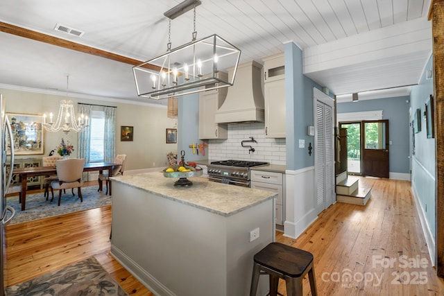 420 S Cedar St, Lincolnton, NC 28092 - kitchen featuring a chandelier, stainless steel stove, custom exhaust hood, light wood finished floors, and a center island